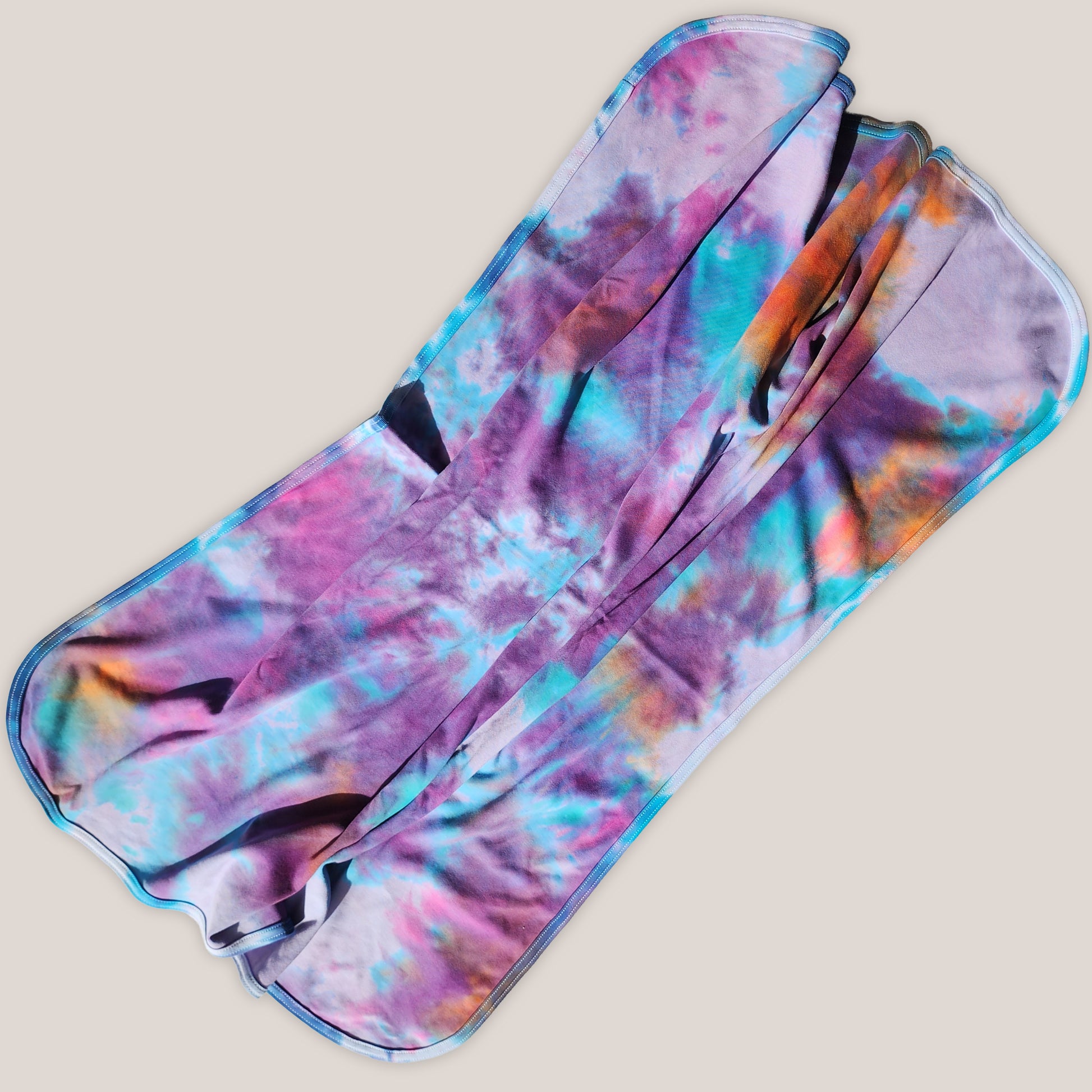 Colorful tie dye baby blanket on a beige background.