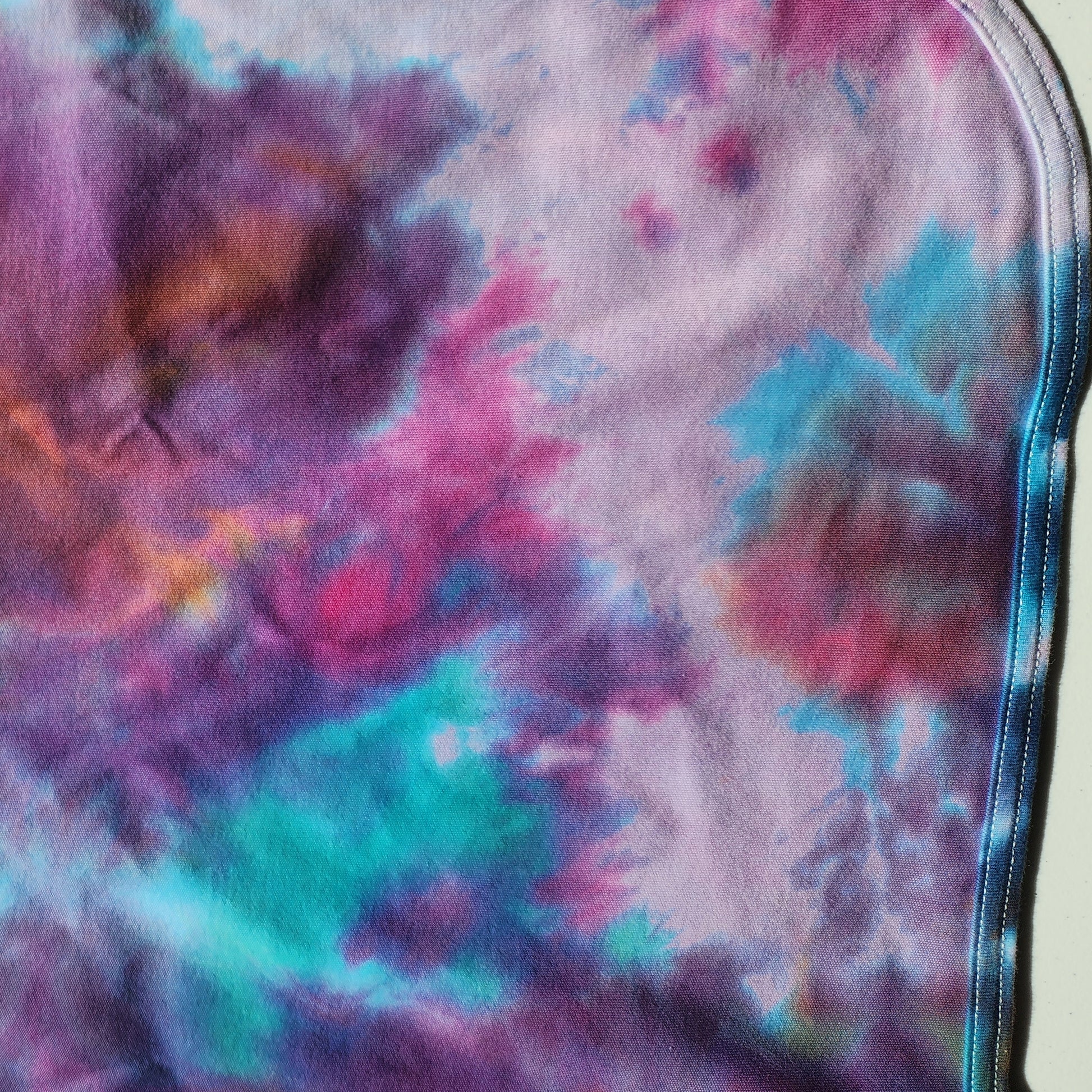 Colorful tie dye baby blanket on a beige background.