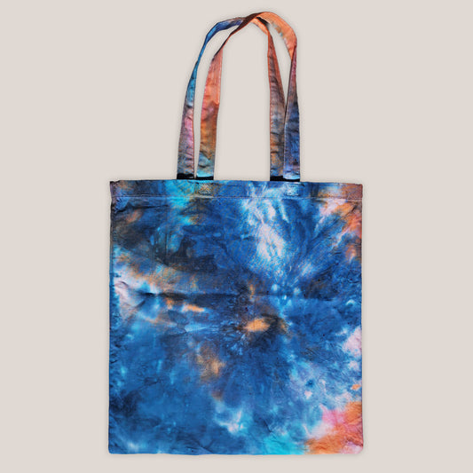 Tie-dye tote bag with a swirling pattern on a beige background
