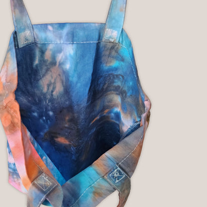 Interior of a tie dye tote bag with a beige background.