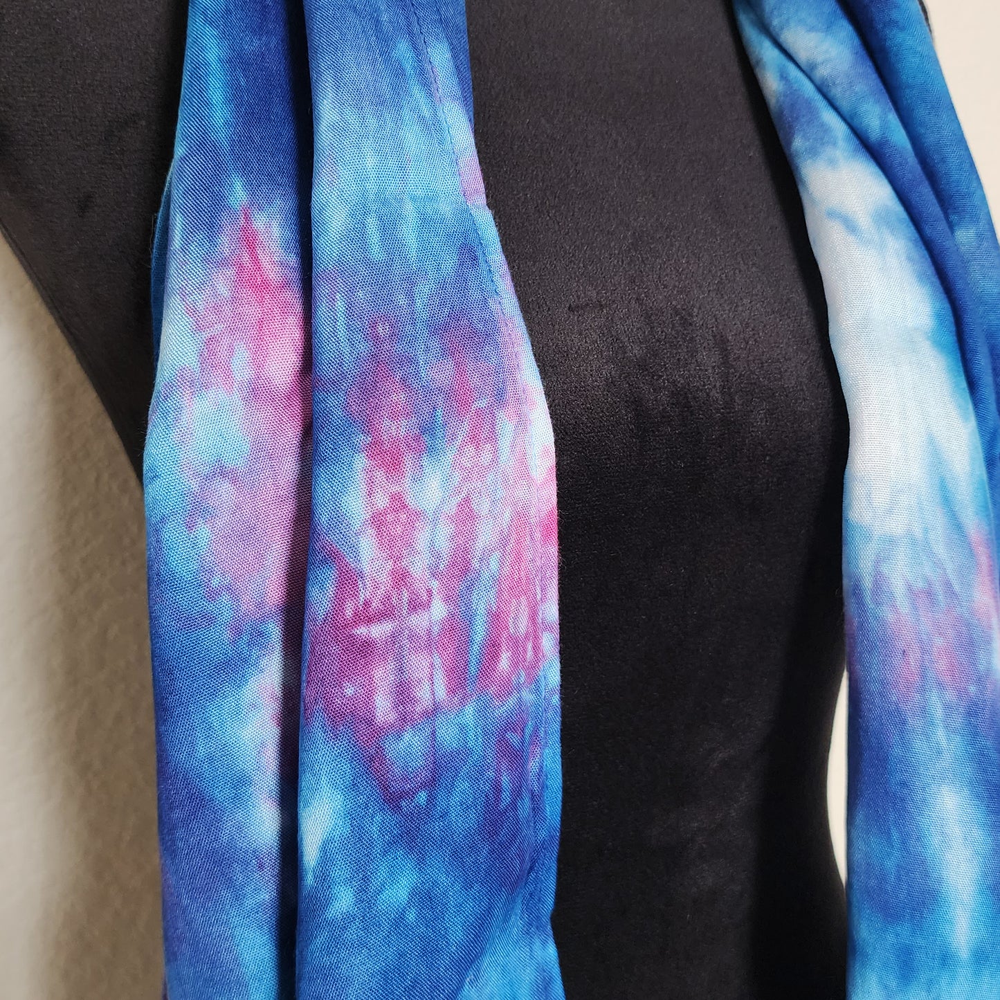 Blue and pink tie-dye scarf draped over a black mannequin.