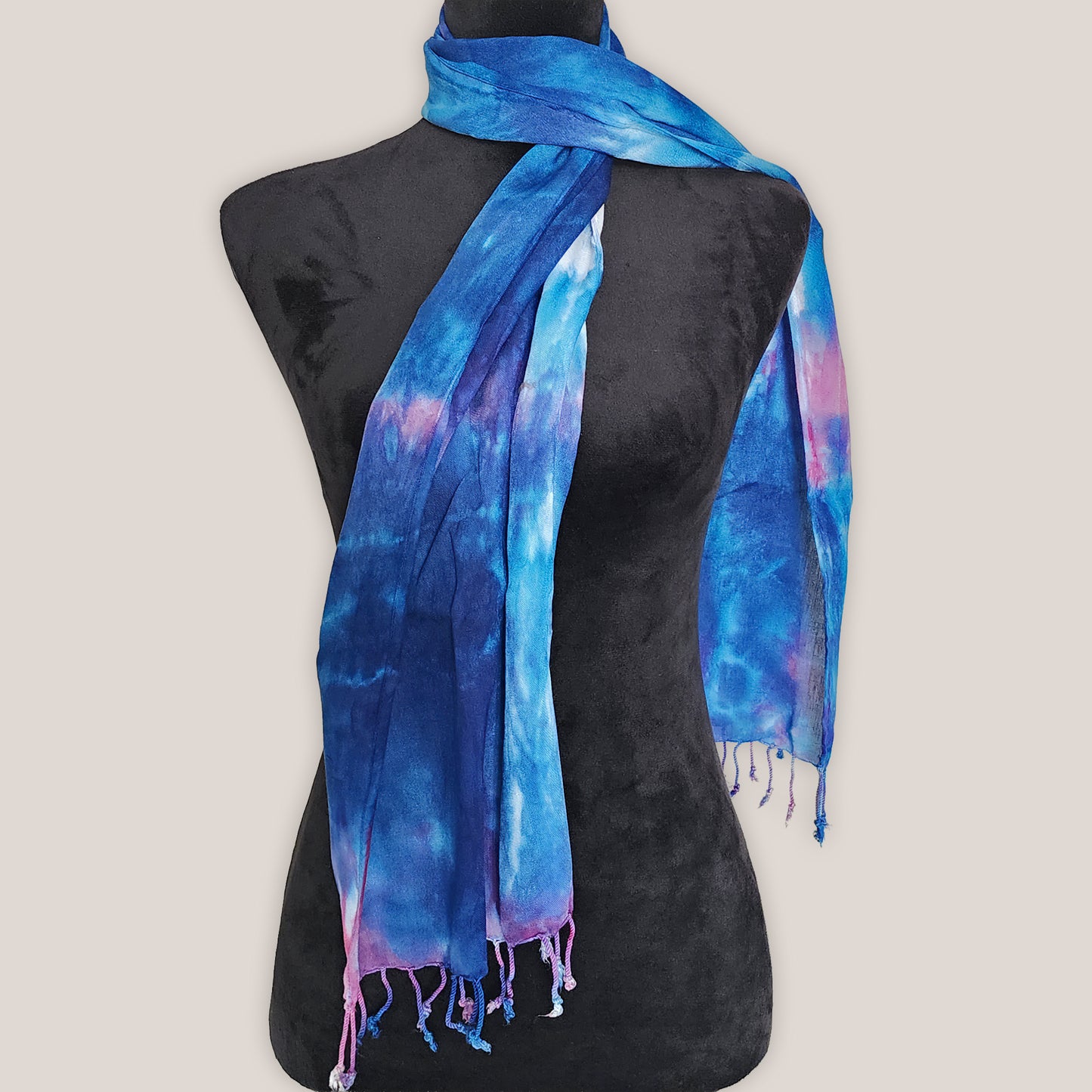 Blue and purple tie-dye scarf on a black mannequin against a plain background