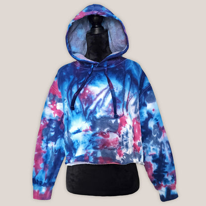 Tie-dye hoodie with blue and pink patterns on a mannequin against a beige background