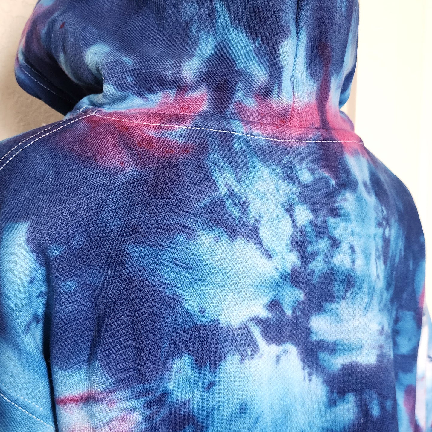 Tie-dye hoodie with blue and purple patterns on a plain background