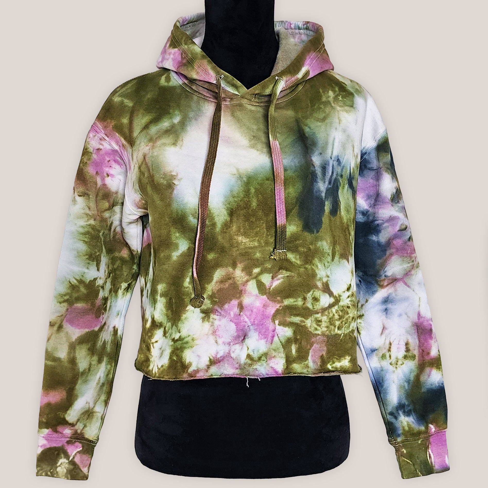 Tie-dye hoodie with pink, green, and black patterns on a beige background