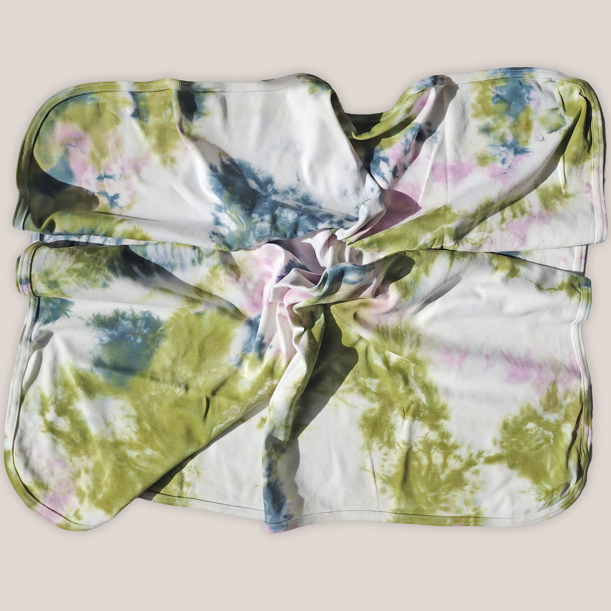 Tie-dye patterned baby blanket on a beige background
