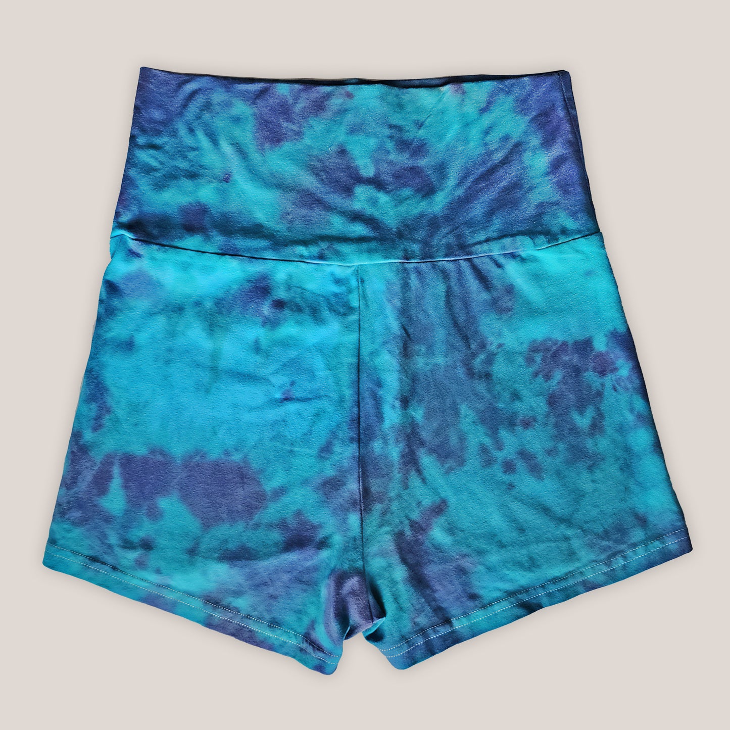 Blue cotton tie-dye shorts on a beige background