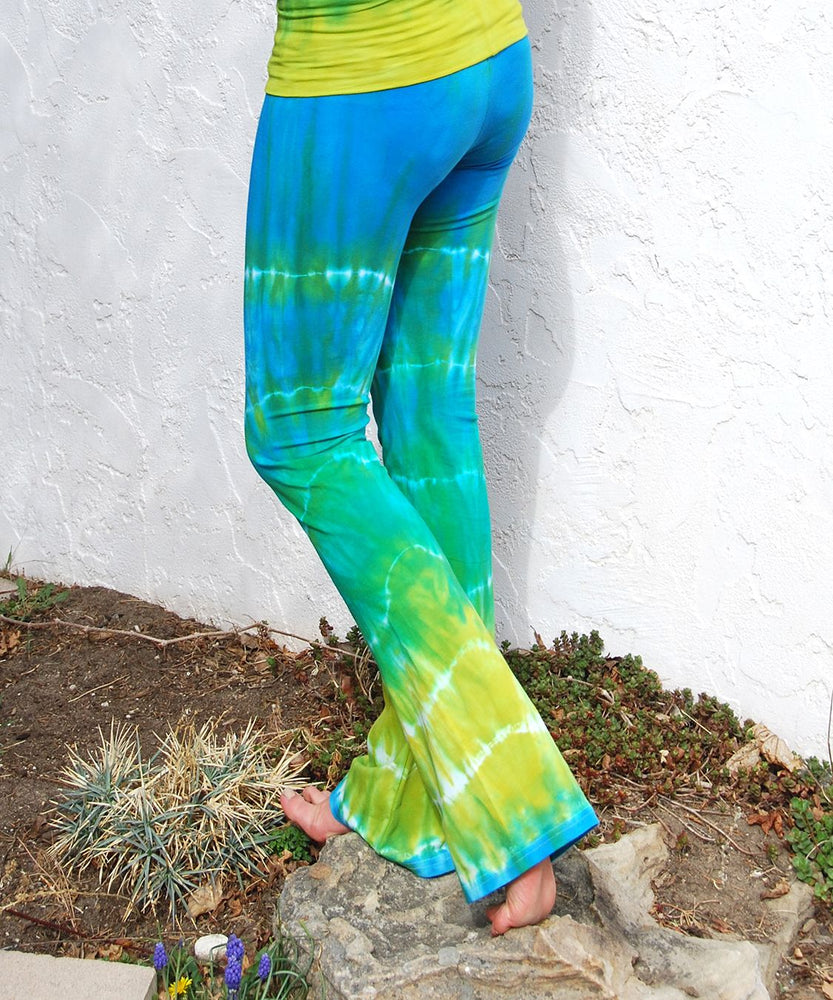 Woman wearing a pair of sustainable cotton blue and green tie dye yoga pants with a fold over waistband.