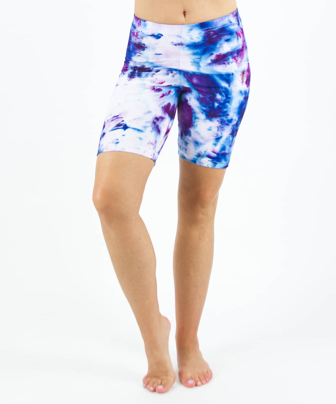 Woman wearing Akasha Sun ice dye tie-dye biker shorts in the colors purple, blue, and white.