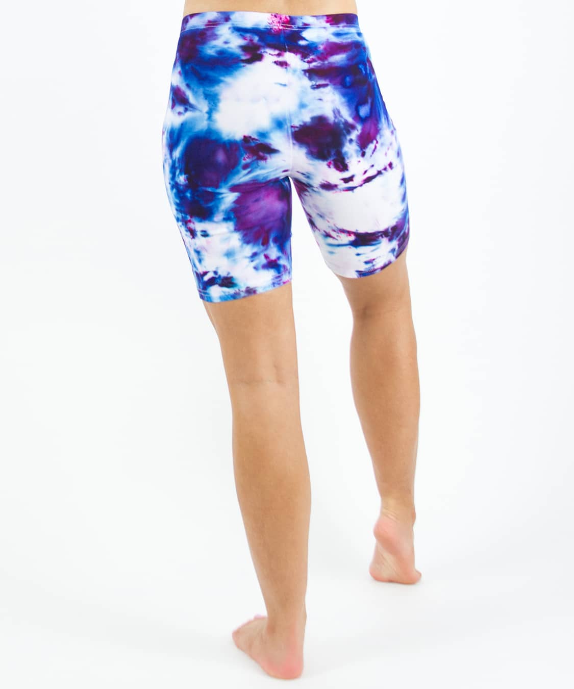 Woman wearing Akasha Sun ice dye tie-dye biker shorts in the colors purple, blue, and white.