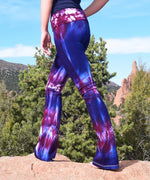 Woman wearing a pair of purple and pink tie dye yoga pants with a fold over waistband.