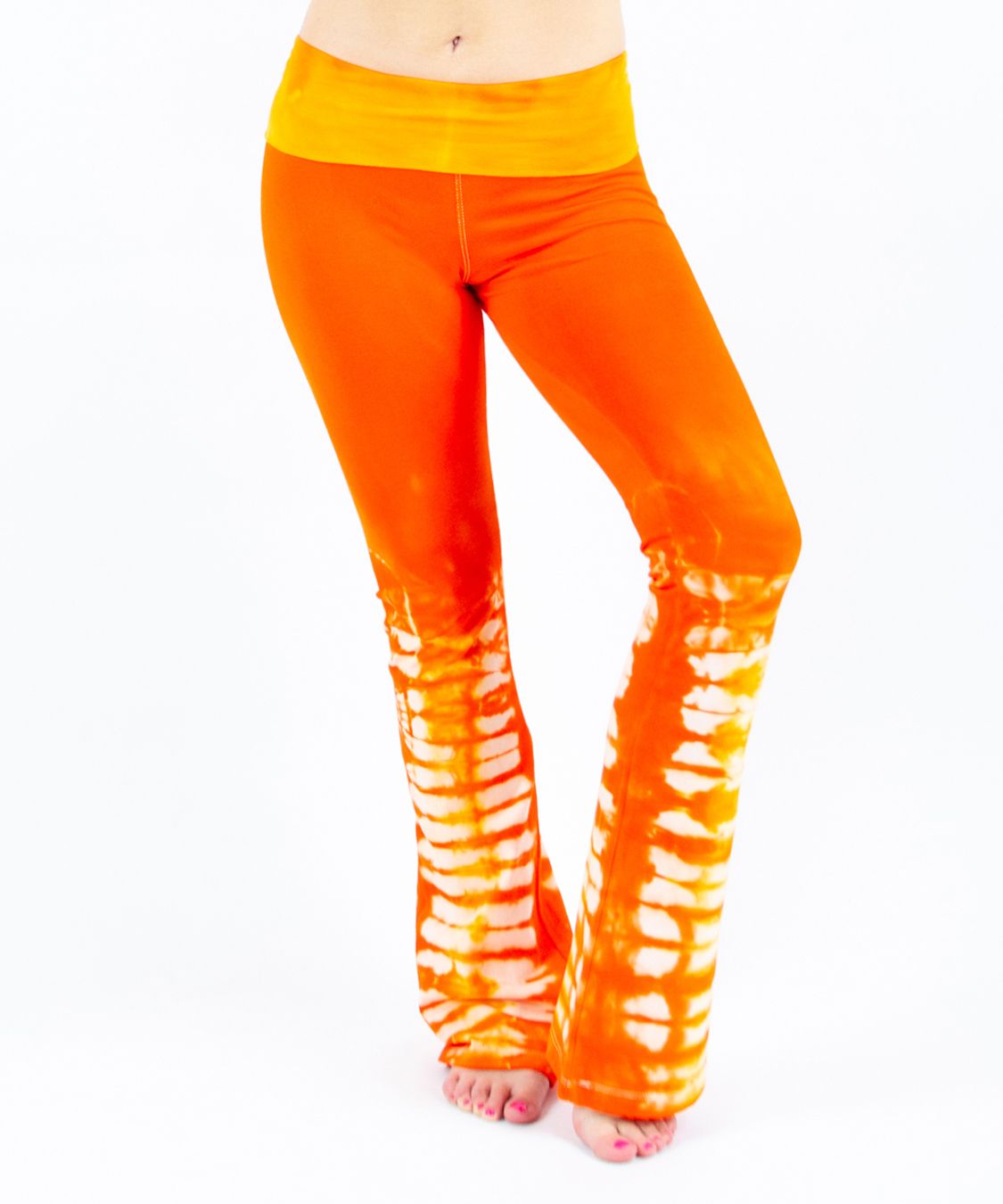 Woman wearing a pair of orange tie dye yoga pants made of sustainable cotton.