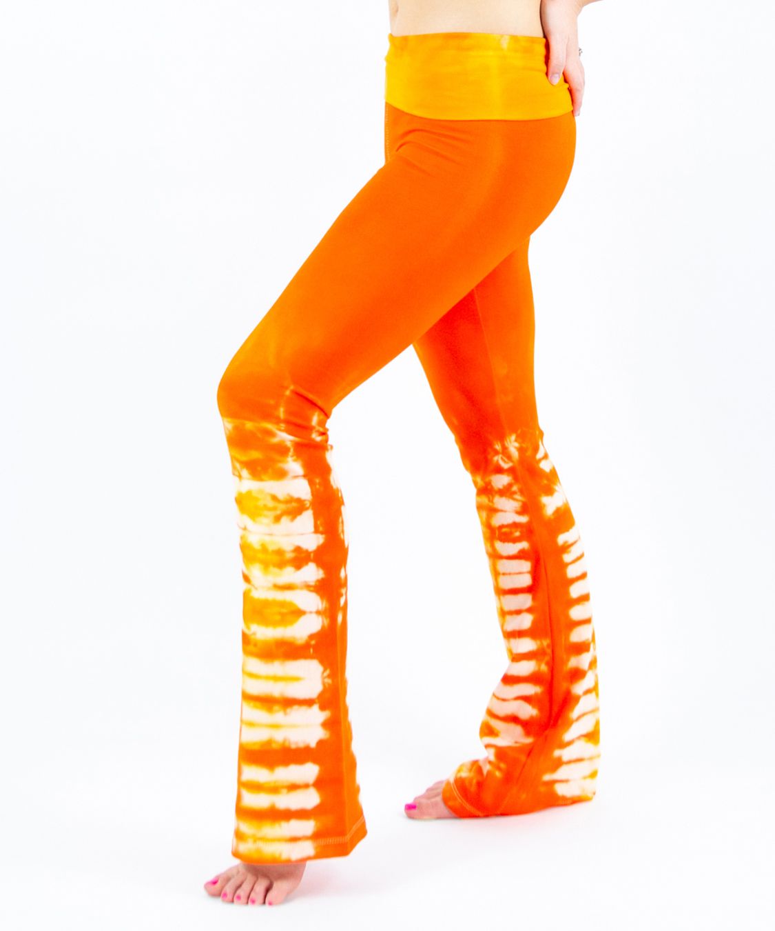 Woman wearing a pair of orange tie dye yoga pants made of sustainable cotton.