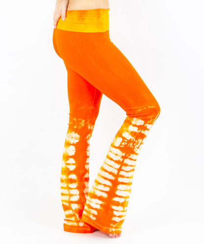 Woman wearing a pair of orange tie dye yoga pants made of sustainable cotton.