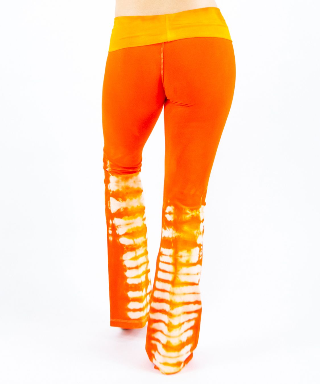 Woman wearing a pair of orange tie dye yoga pants made of sustainable cotton.