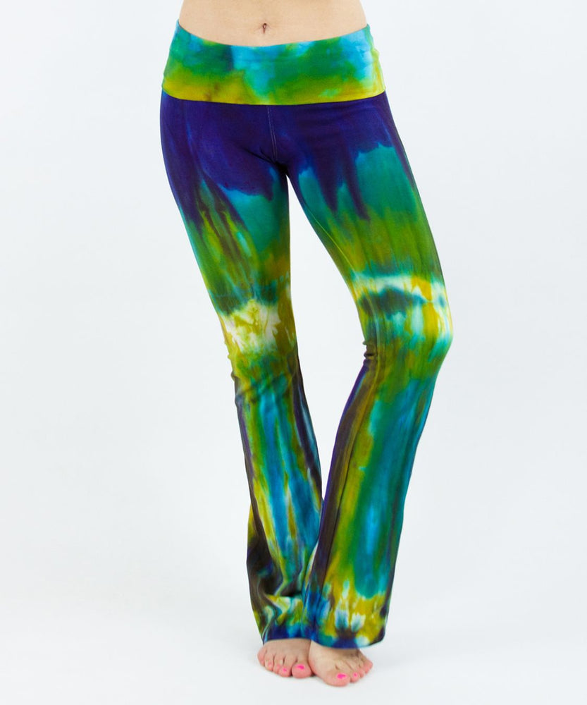 Woman wearing a navy blue and green tie dye yoga pants featuring a fold over waistband.