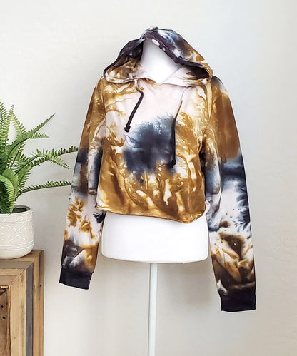 An amber and black tie dye hoodie crop top featuring long sleeves and draw strings.