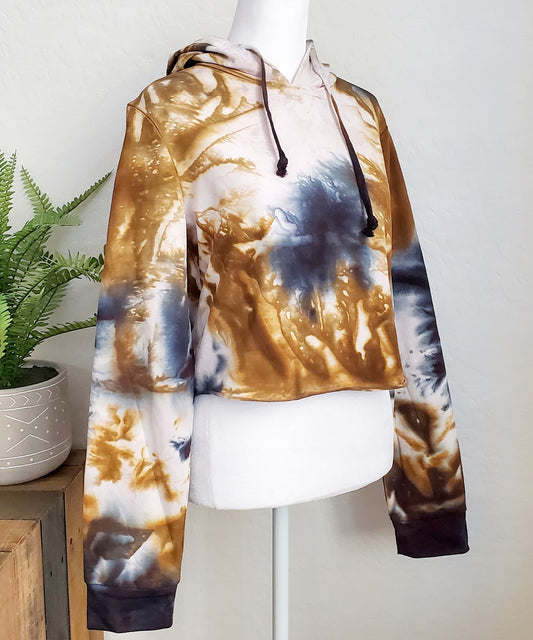 An amber and black tie dye hoodie crop top featuring long sleeves and draw strings.