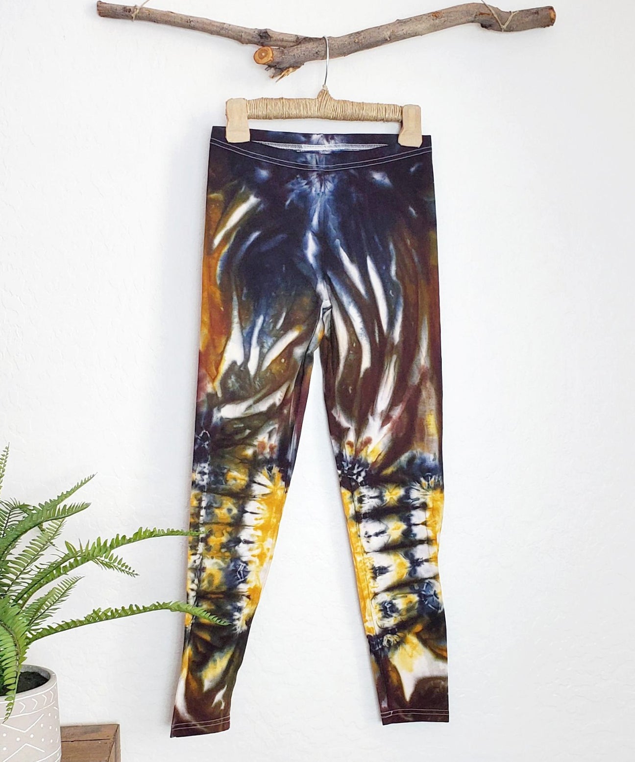 A pair of tie dye leggings in amber, black, and yellow.