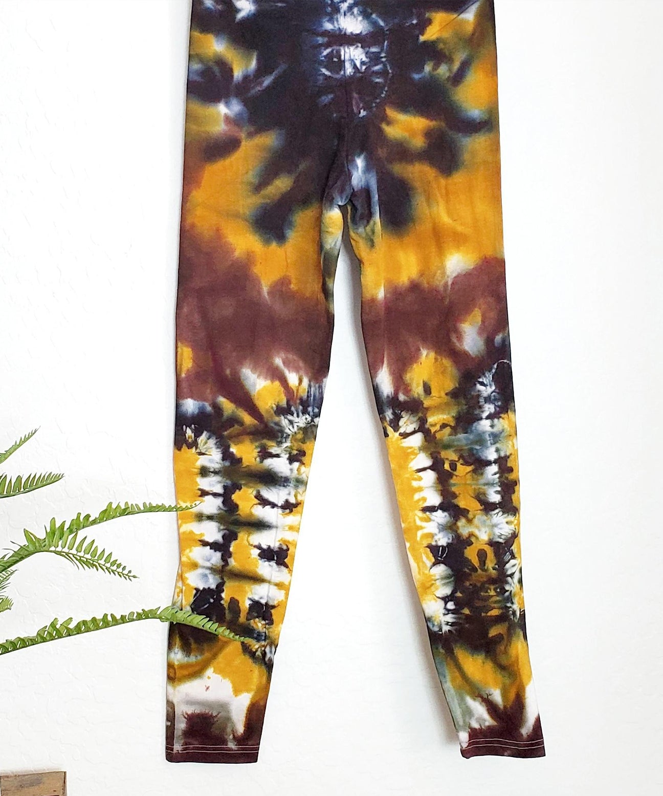 A pair of tie dye leggings in amber, black, and yellow.