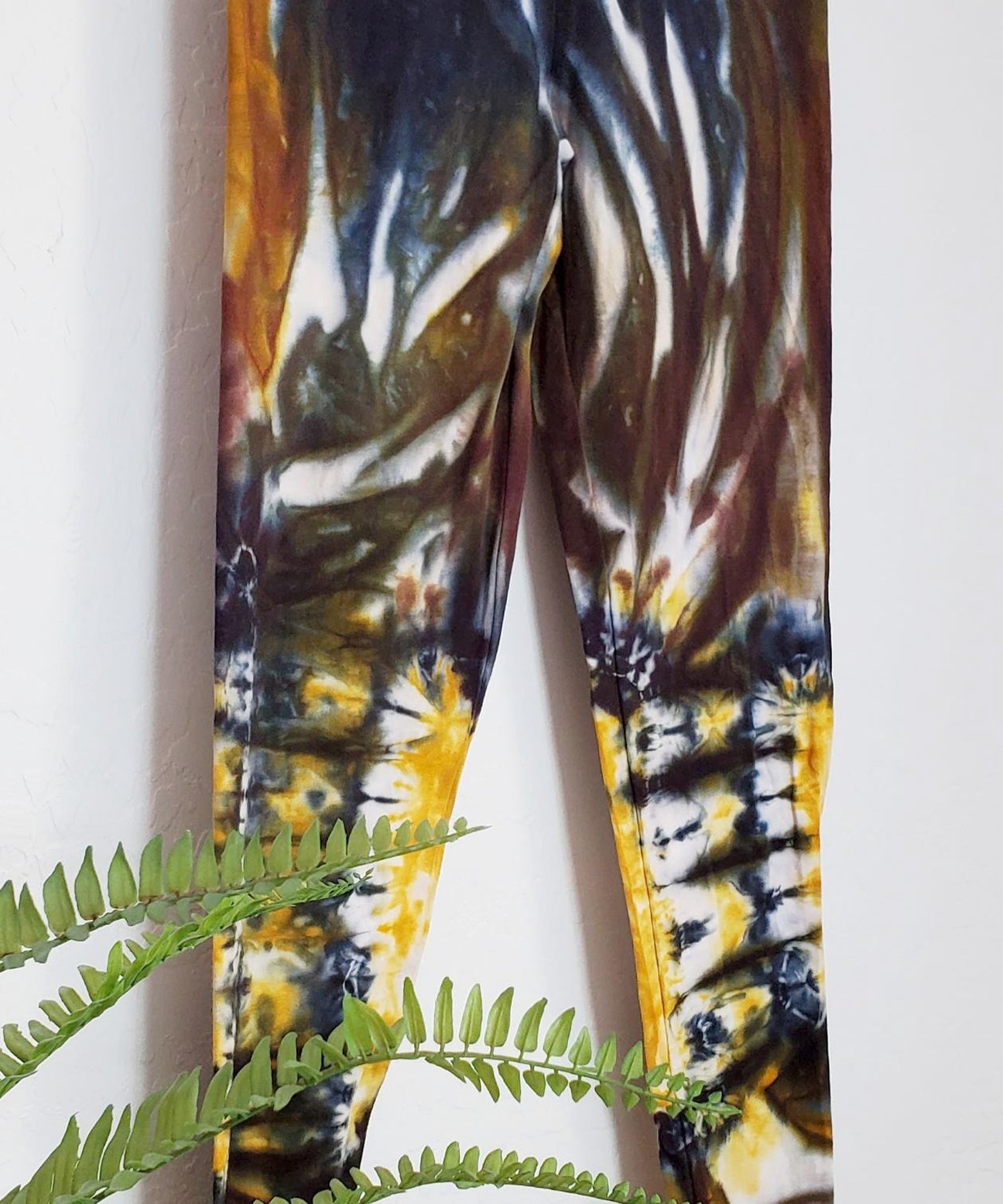 A pair of tie dye leggings in amber, black, and yellow.