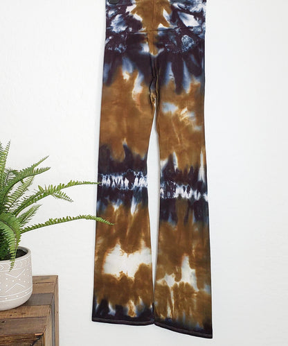 An amber and black tie dye pair of yoga pants featuring a wide waistband.