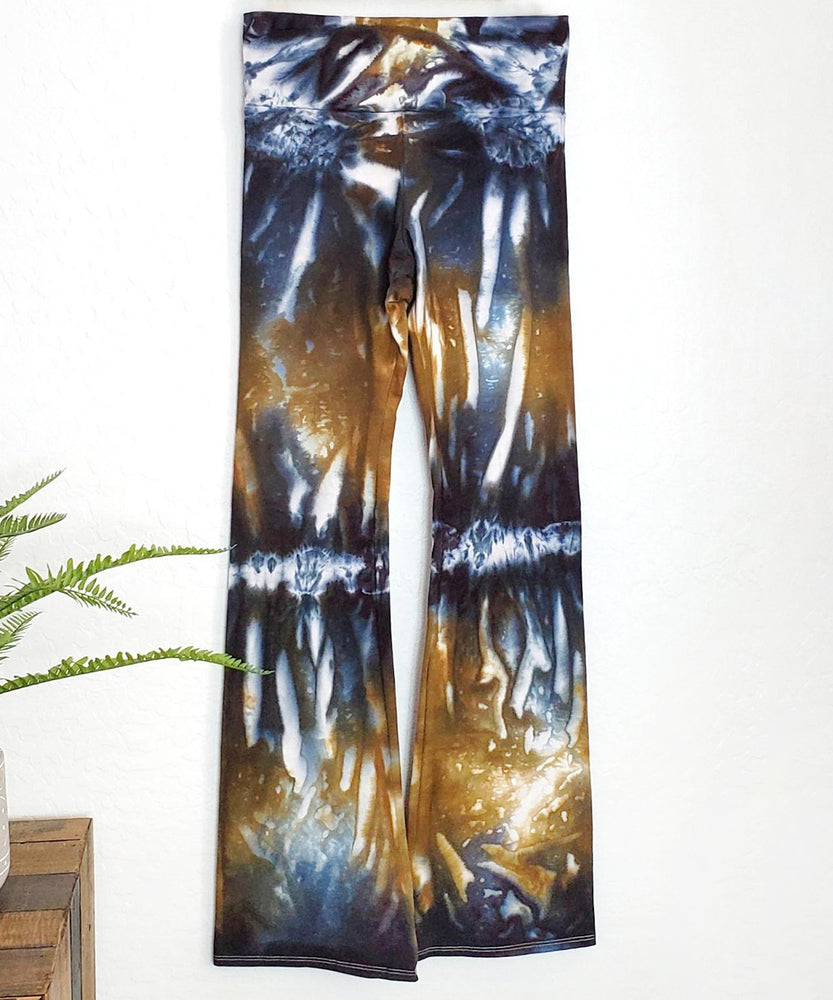 An amber and black tie dye pair of yoga pants featuring a wide waistband.
