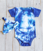A blue and white tie dye baby bodysuit with a matching hat.