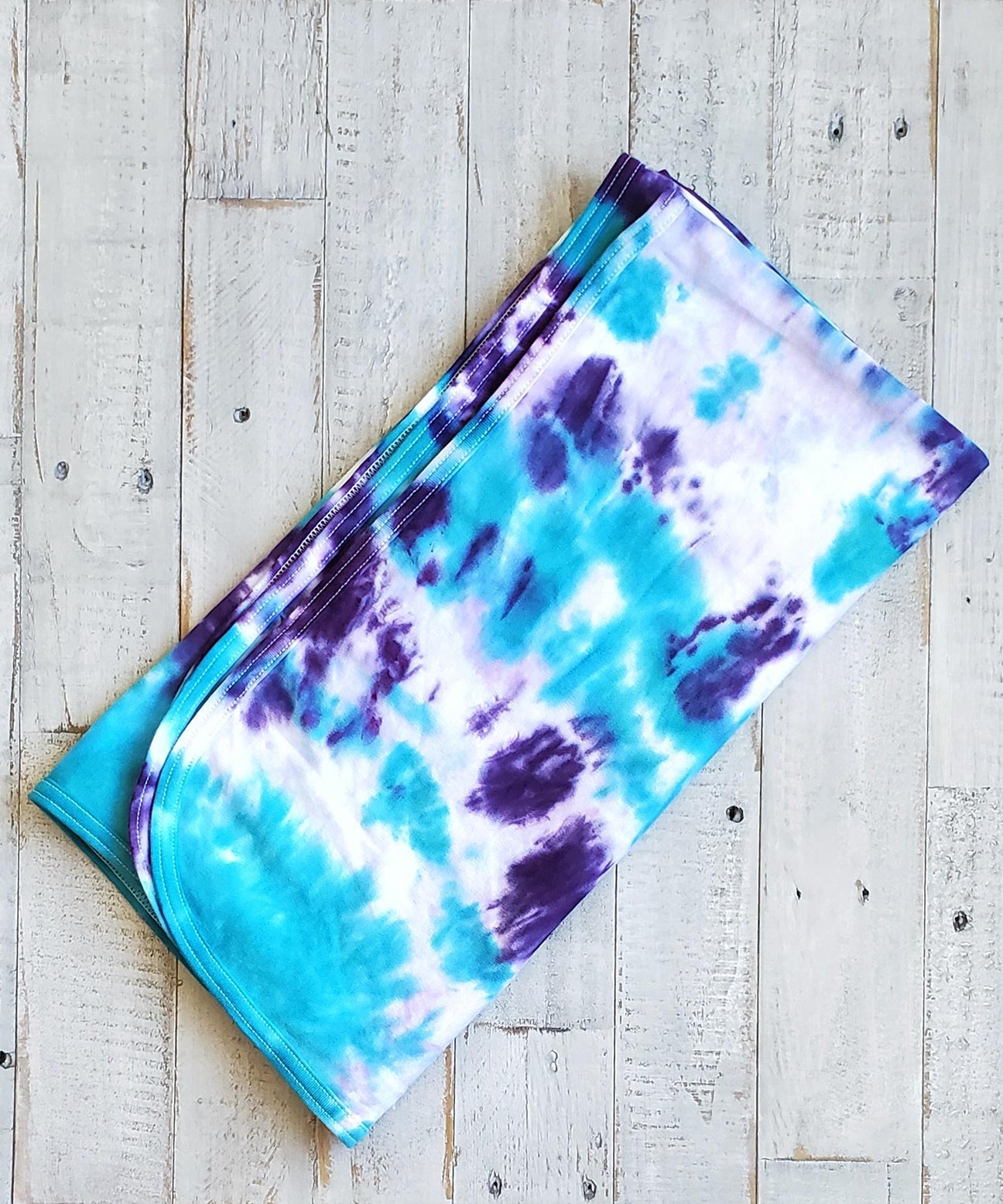 A teal and purple tie dye organic baby blanket.