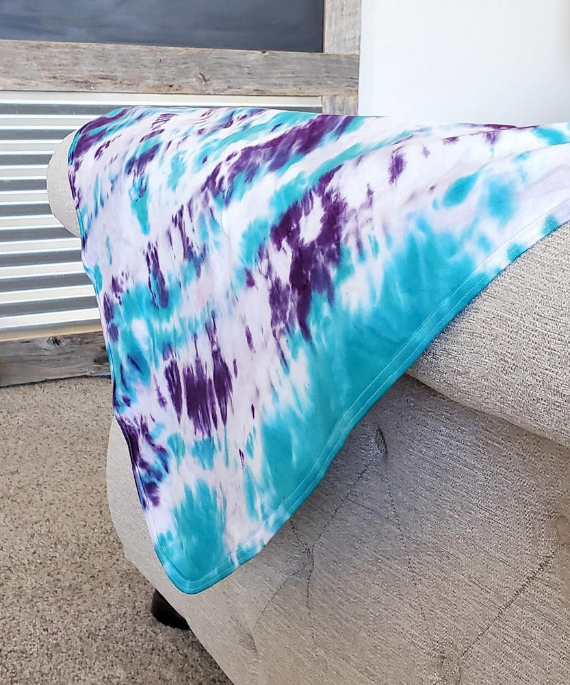 A teal and purple tie dye organic baby blanket.