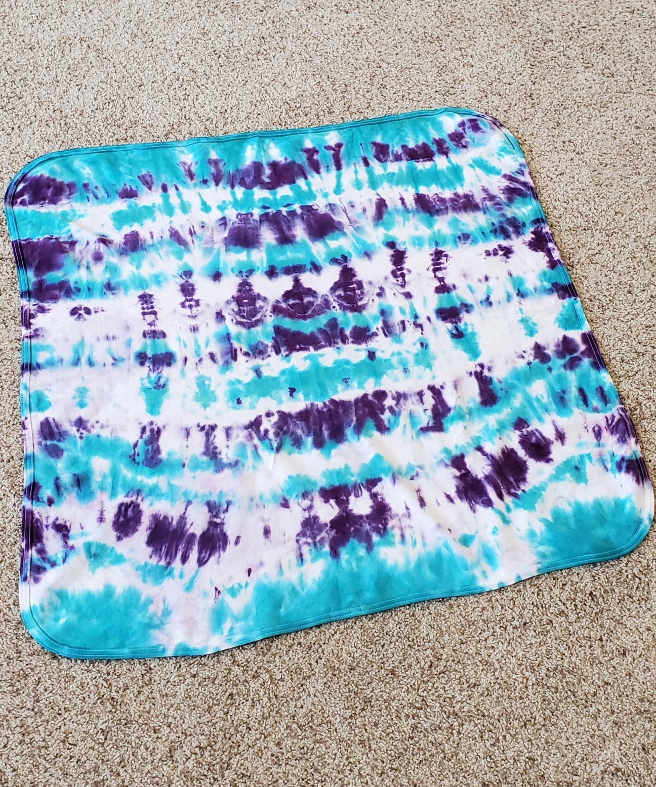 A teal and purple tie dye organic baby blanket.