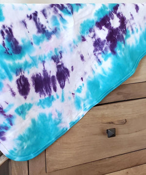 A teal and purple tie dye organic baby blanket.