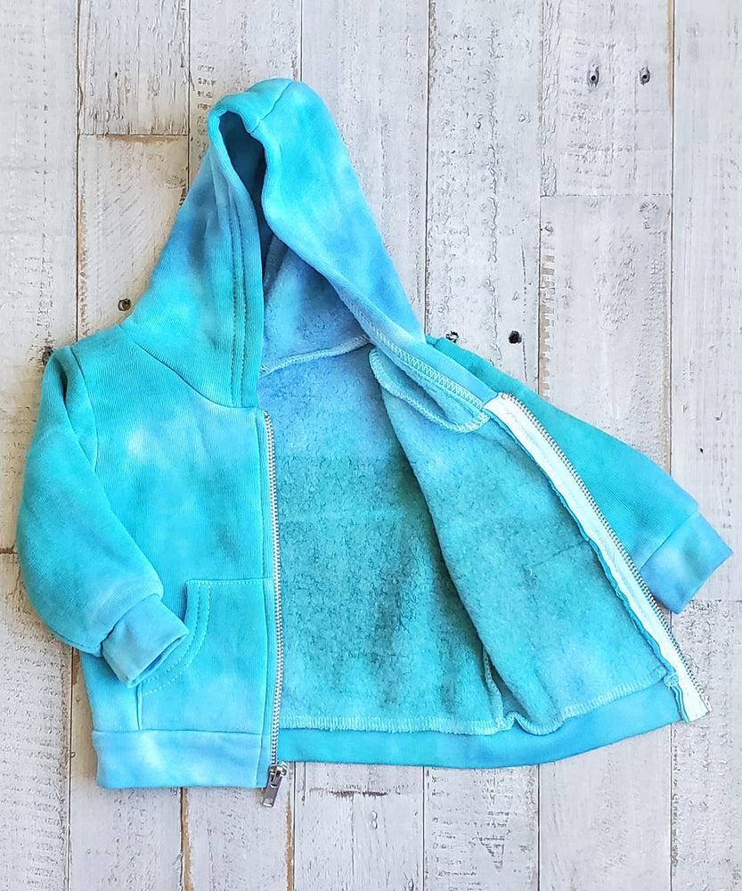 An aqua blue tie dye baby jacket with fleece interior, pockets, and hood.