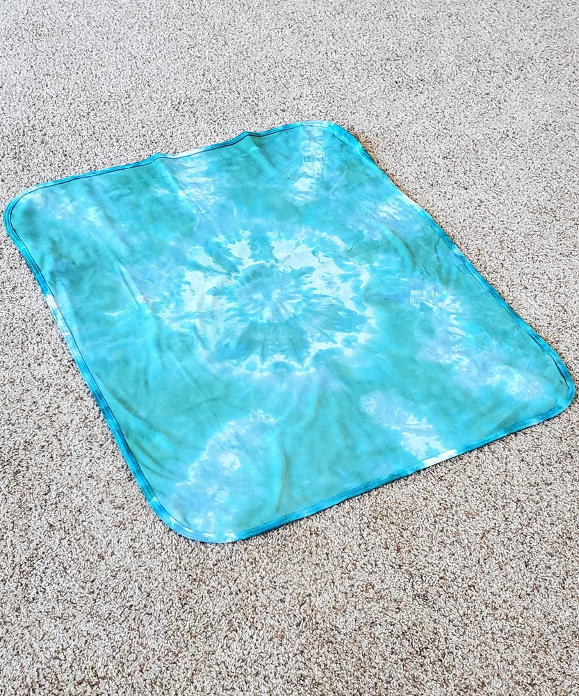 
                
                    Load image into Gallery viewer, An aqua blue tie dye baby bodysuit, blanket, and hat set.
                
            