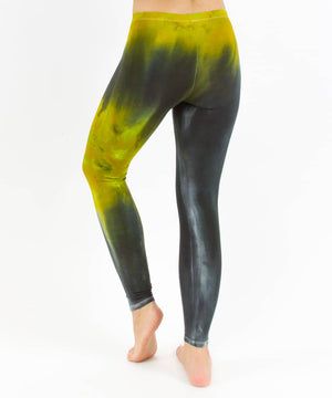 Woman wearing a pair of black and green chakra tie dye leggings made of sustainable cotton.