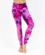Woman wearing a pair of pink and purple ice dye tie dye leggings made of sustainable cotton.