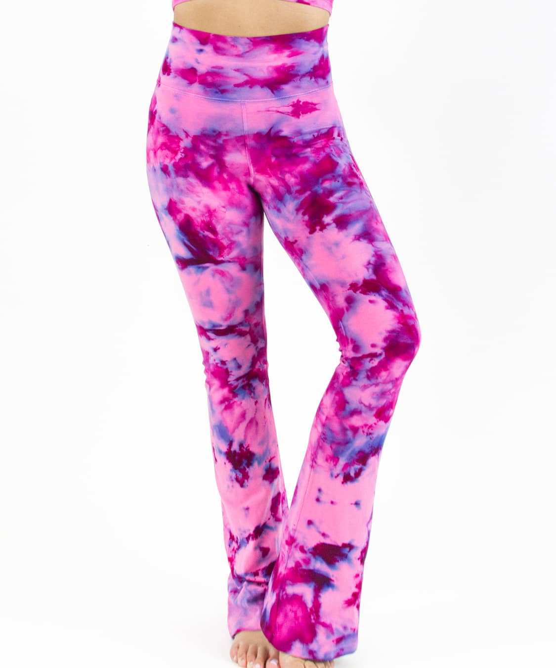 Woman wearing a pair of fold over tie dye yoga pants in the colors pink and purple.