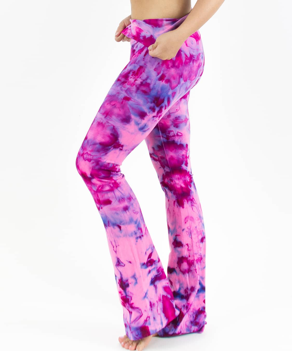 Woman wearing a pair of fold over tie dye yoga pants in the colors pink and purple.