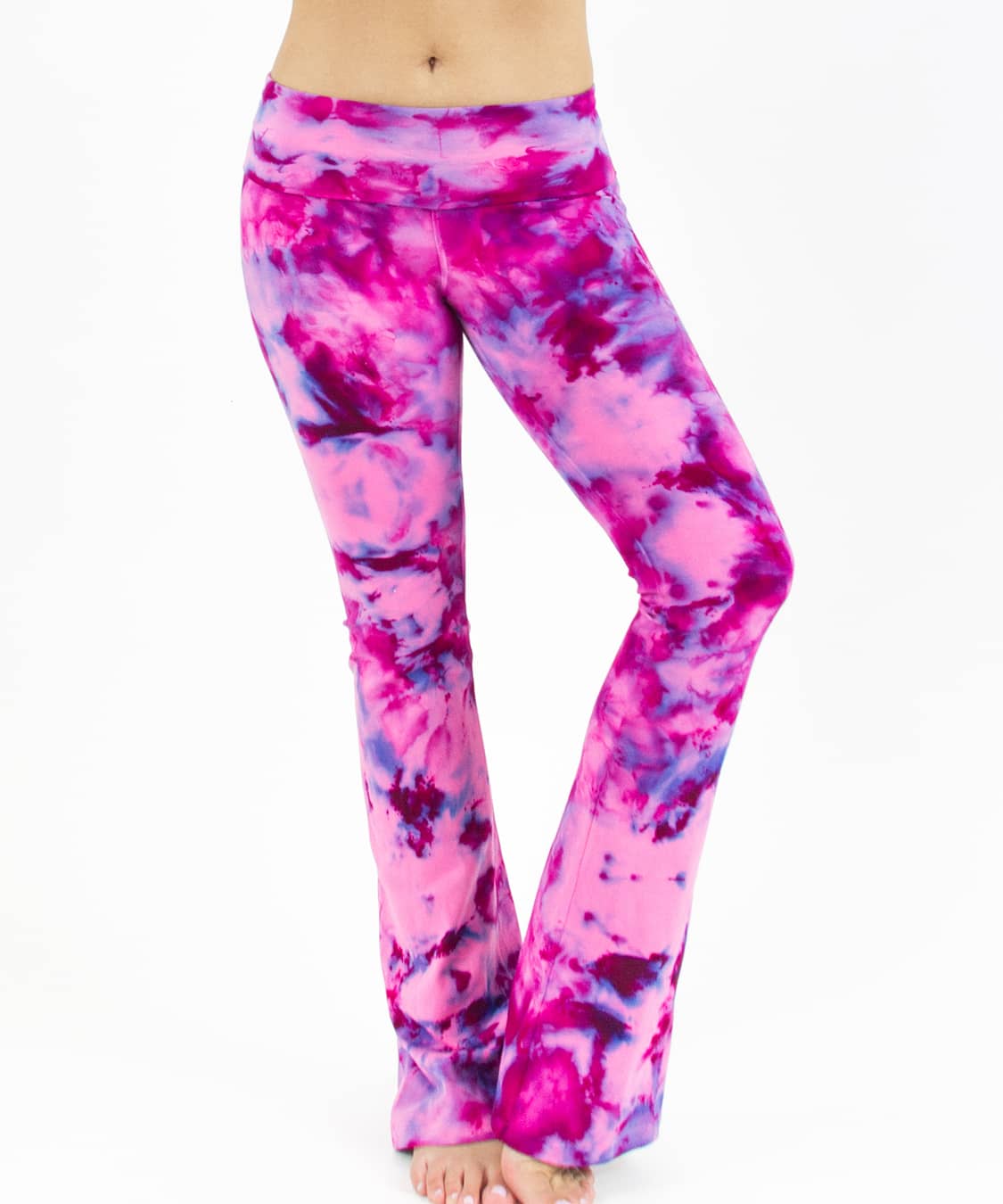 Woman wearing a pair of fold over tie dye yoga pants in the colors pink and purple.