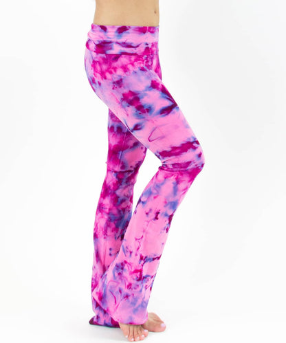 Woman wearing a pair of fold over tie dye yoga pants in the colors pink and purple.