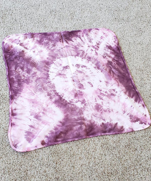 A dusty rose pink organic tie dye baby blanket.