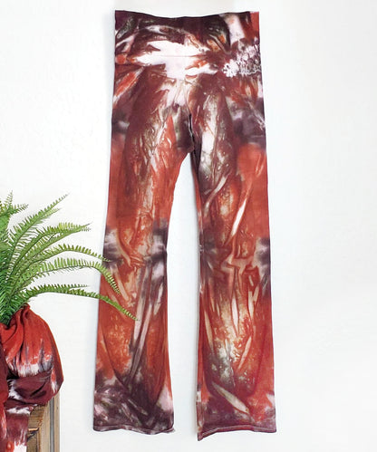 A rust and brown tie dye pair of yoga pants featuring a wide waistband.