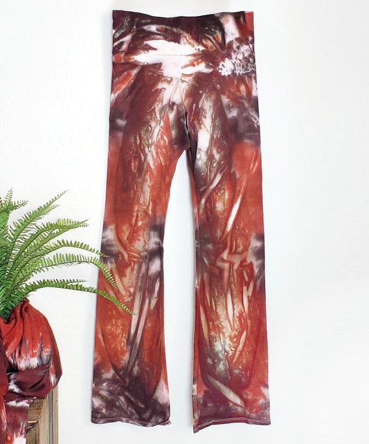 A rust and brown tie dye pair of yoga pants featuring a wide waistband.