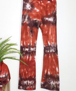 A rust and brown tie dye pair of yoga pants featuring a wide waistband.