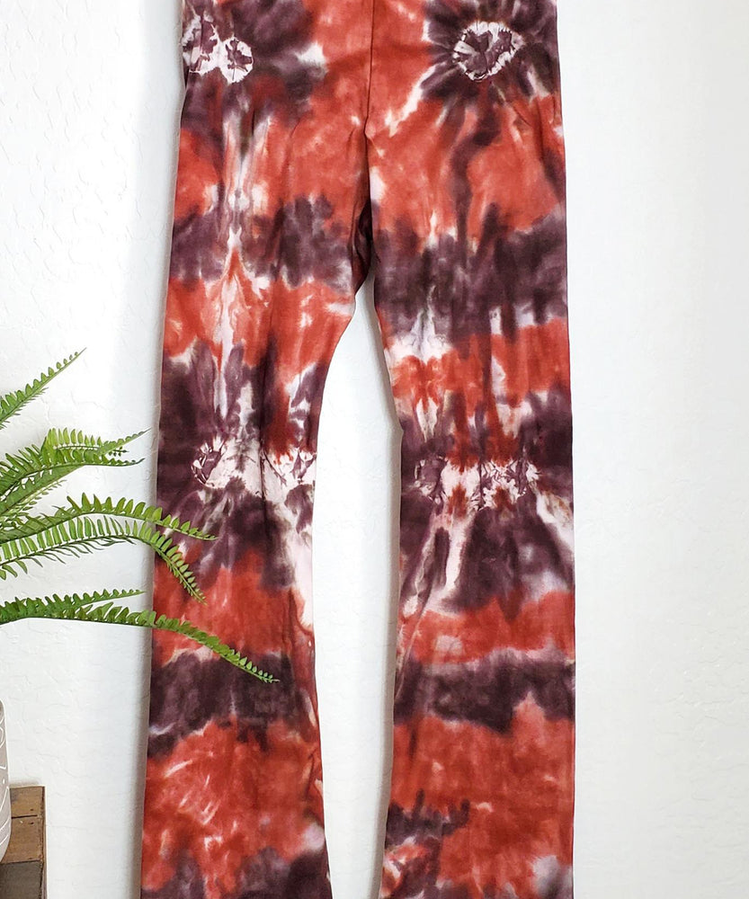 A rust organic and brown tie dye pair of yoga pants with a wide waistband.