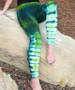 Woman wearing the Emerald Dragon tie dye leggings in green.