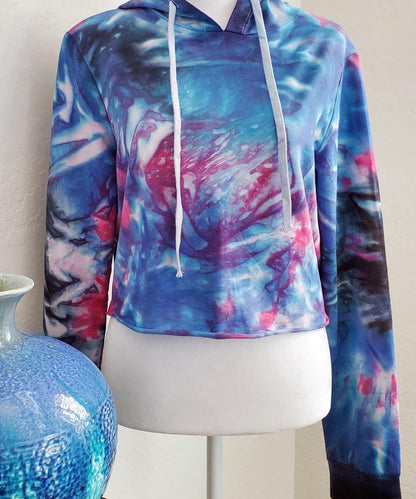 Blue, pink and black tie dye hoodie crop top with long sleeves and draw strings.