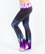 Woman wearing a pair of Akasha Sun sustainable cotton tie dye yoga pants in the colors black and purple.