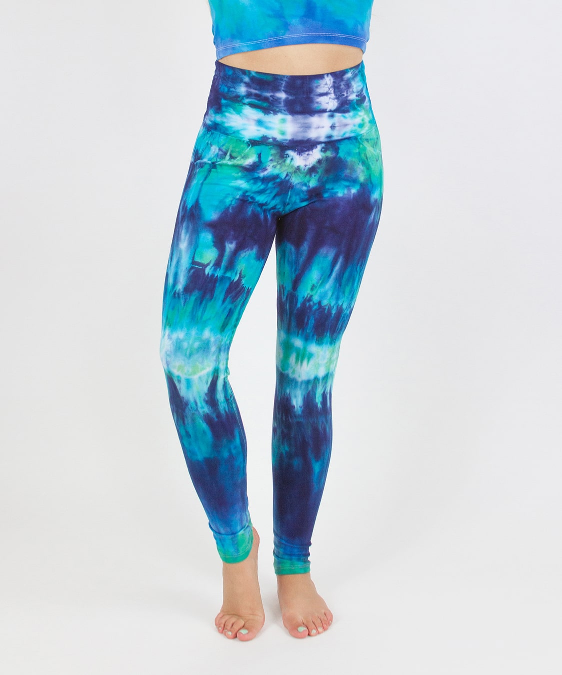 Woman wearing the Galapagos Islands tie dye fold over leggings that feature navy blue, teal, and aqua.