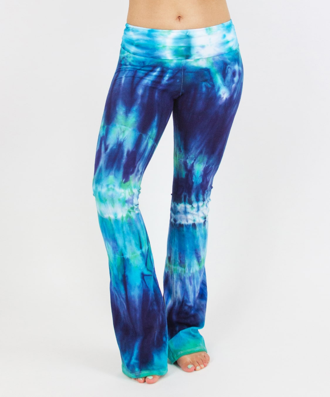 Woman wearing the Galapagos Islands tie dye yoga pants that features hand-dyed hues of navy blue, teal, and aqua.  These pants include a fold over waistband that is also comfortable as maternity wear.